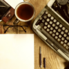 A typewriter and coffee on a desk.