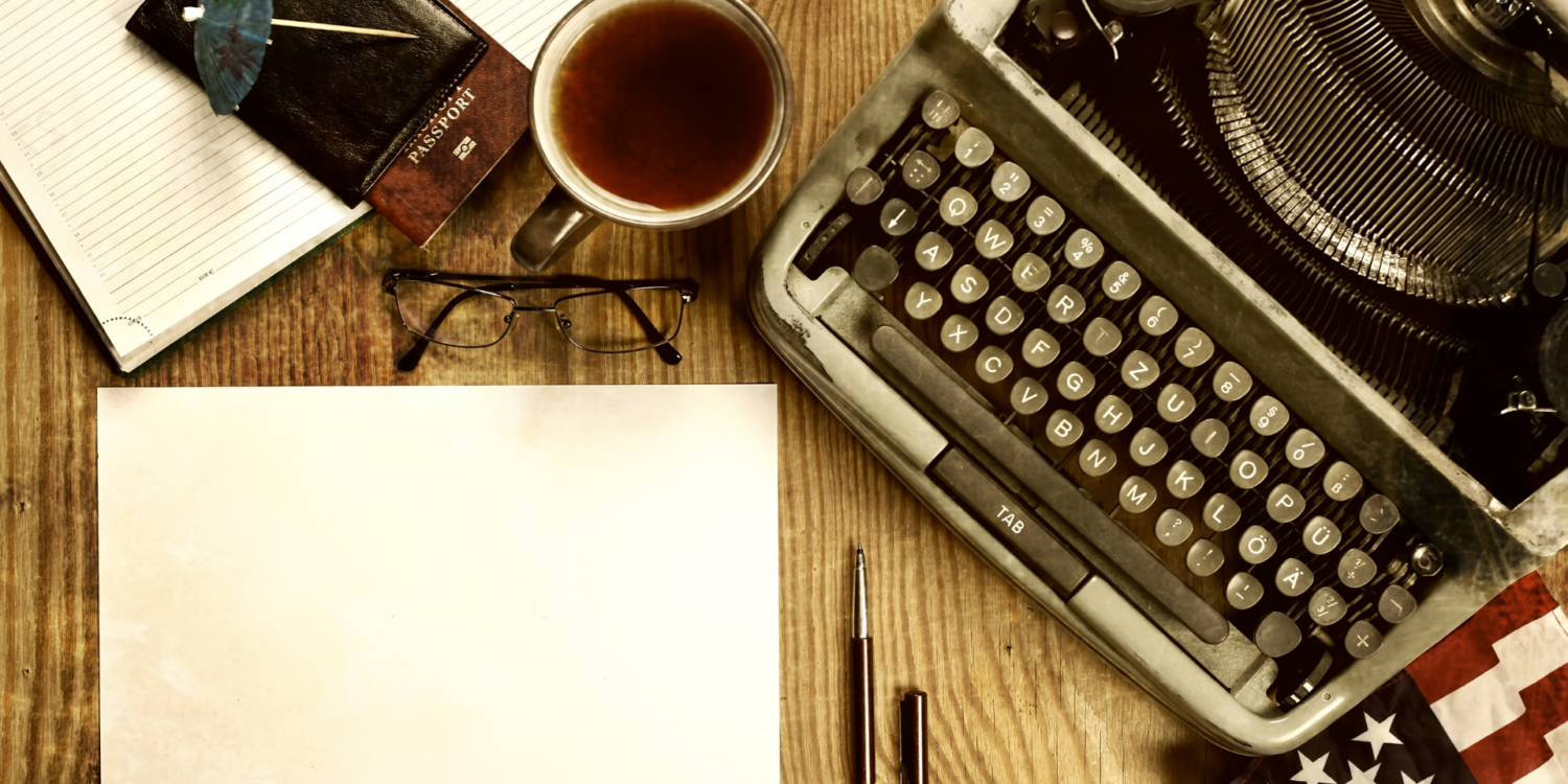A typewriter and coffee on a desk.