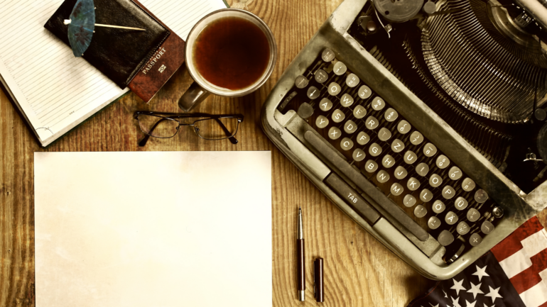 A typewriter and coffee on a desk.